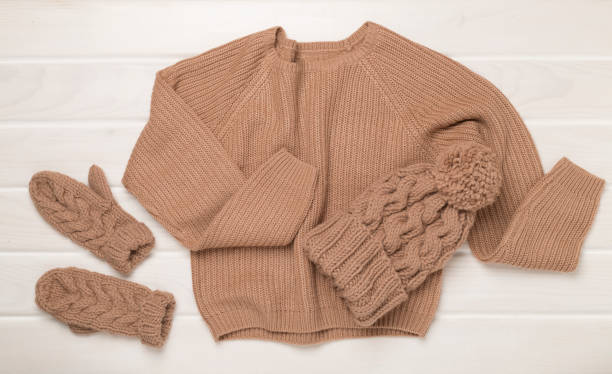 istock Sweater and winter hat with mittens on wooden background, top view. 2188927735