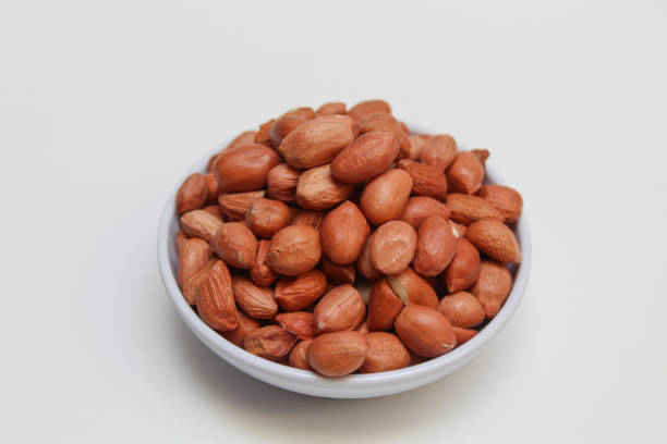 Peanuts or groundnut, or goober, or monkey nut. Peeled peanuts with thin red skin. Isolated on white background