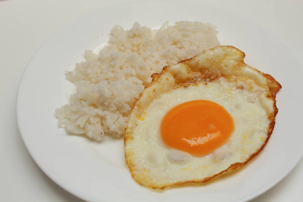 Sunny side up or fried egg with rice on white plate. Isolated on white background