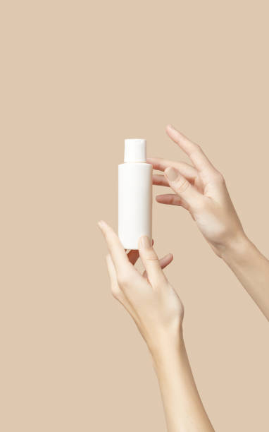 istock A womans hands holding a white cosmetic bottle on a beige background 2188932213