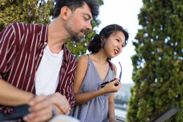 Two friends having a casual conversation outdoors amid lush greenery, capturing a moment of relaxation and enjoyment on a sunny day.