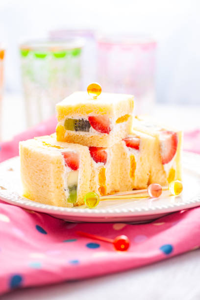 Soft Japanese fruit sandwiches filled with strawberries, kiwi, and whipped cream, garnished with colorful picks