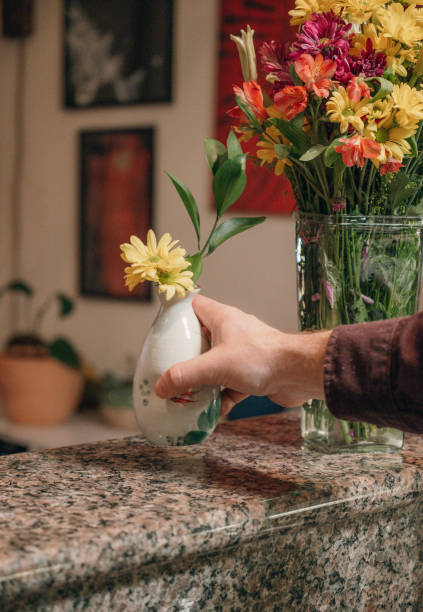 istock Man arranging flowers in vase at home 2188948014