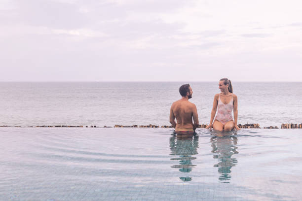 istock Couple Relaxing by Infinity Pool Overlooking Ocean 2188951695