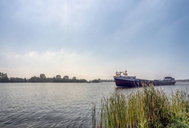 istock Cargo ship on a calm river with reeds and trees. 2188956810