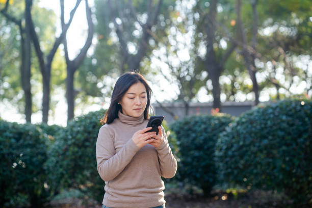 istock asian female using smart phone outdoor 2188965538