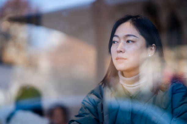istock asian female looking through window 2188966502
