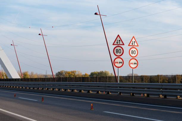 A sign indicating a traffic lane on the route before the bridge while the sun is about to set.