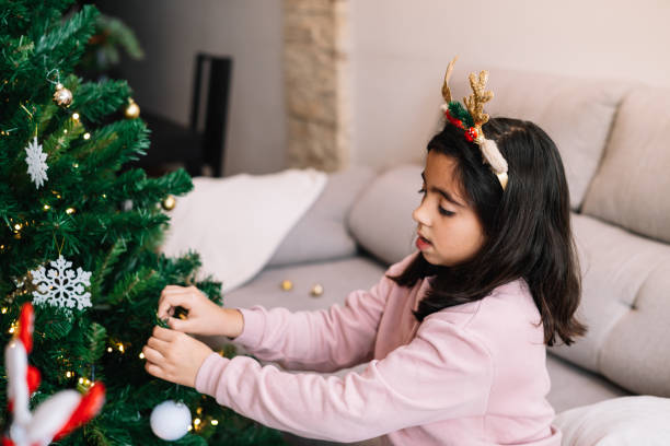 istock A young girl is decorating a Christmas tree with ornaments. 2188975676