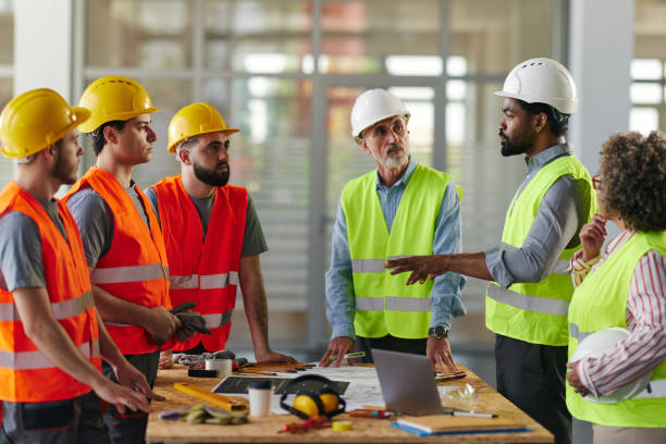 istock Team of architects and manual workers talking at construction site. 2188976758