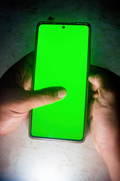 istock A person holding a smartphone with a bright green screen, highlighting the device's display and touch interaction. Ideal for technology and gadget themes 2188977249