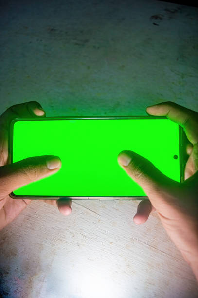 istock Hands holding a smartphone with a bright green screen, illuminated in a dark setting, highlighting the contrast. Ideal for showcasing technology, gadgets, or smartphone usage 2188977429