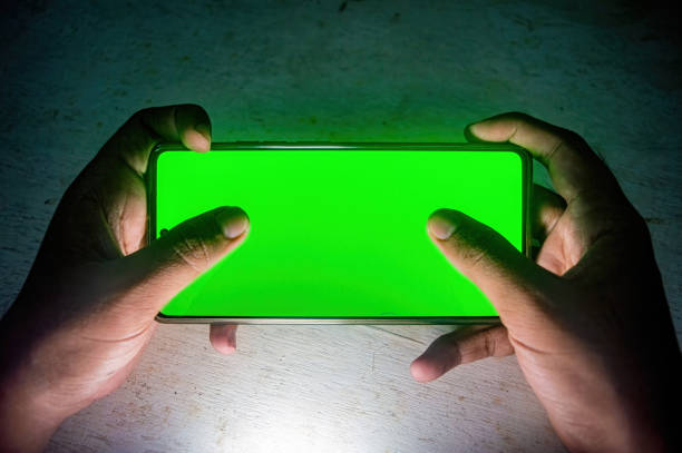 istock Hands holding a smartphone with a bright green screen, illuminated in a dark setting, highlighting the contrast. Ideal for showcasing technology, gadgets, or smartphone usage 2188977435