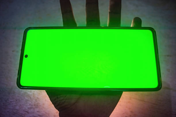 istock A hand holding a smartphone with a bright green screen, highlighting the device's front camera and sleek design. Perfect for tech, display, or green screen concepts 2188977707