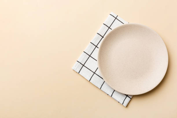istock Top view on colored background empty round white plate on tablecloth for food. Empty dish on napkin with space for your design 2188978796