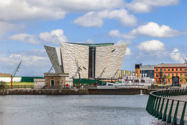 Belfast - Ireland. May 25, 2024: Titanic Museum in Belfast with its modern angular architecture, set against a bright blue sky and reflected in the surrounding water
