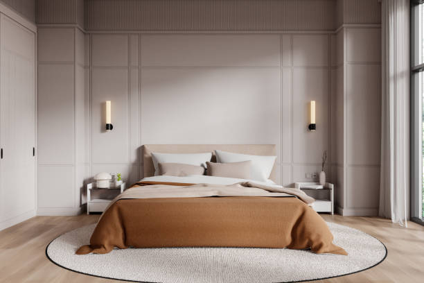 istock Modern bedroom interior with a neutral color palette, featuring a large bed with beige and brown bedding, wall lights, and a cozy round rug. 3D Rendering 2188983500