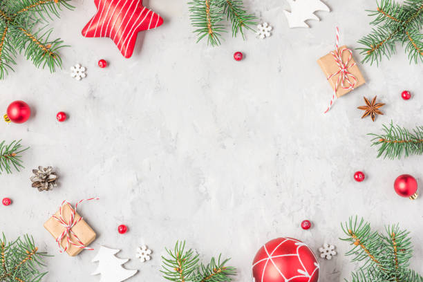 istock Christmas frame made of fir branches, red decorations, gift boxes and pine cones on gray concrete background. Flat lay. Happy New Year and winter holidays background. Top view 2188984589