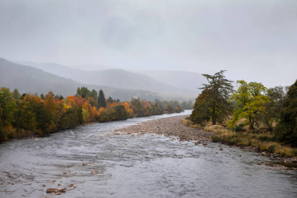 This is a scenic landscape from a high angle view with a lake in the Scotland Highlands with autumn leaf foliage on an overcast October day.