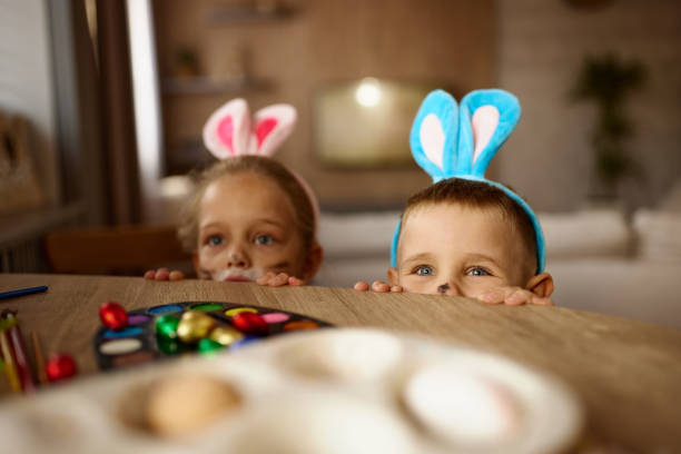 istock Carefree kids having fun behind the table on Easter at home. 2188986379
