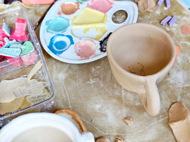 istock Workshop for kids. Children learning how to use clay for making dishes. 2188986429