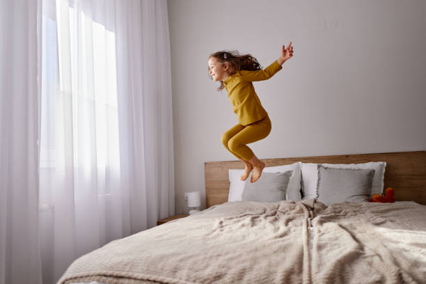 istock Carefree girl having fun while jumping on the bed. 2188986435