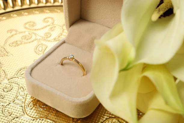 istock Wedding ring in case and flowers on golden background, close up 2188988038