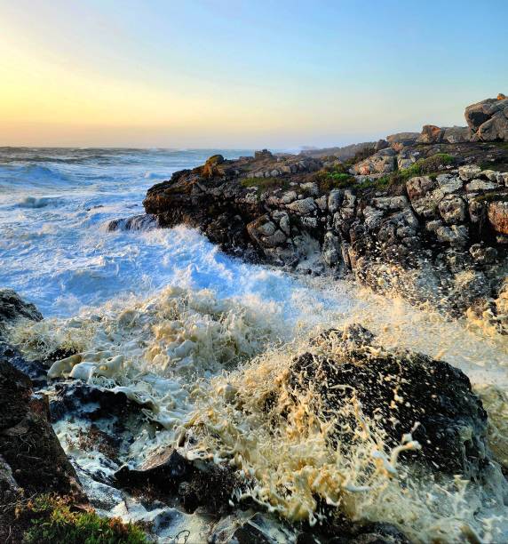 istock Stormy seas with foam covered wave breaking over rocks. 2188988319