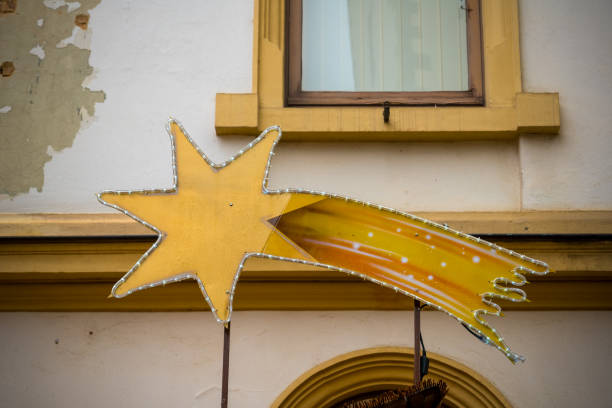 A vibrant yellow star decoration with a comet tail is showcased on a building. It adds a whimsical touch to the urban landscape, attracting attention during the day.