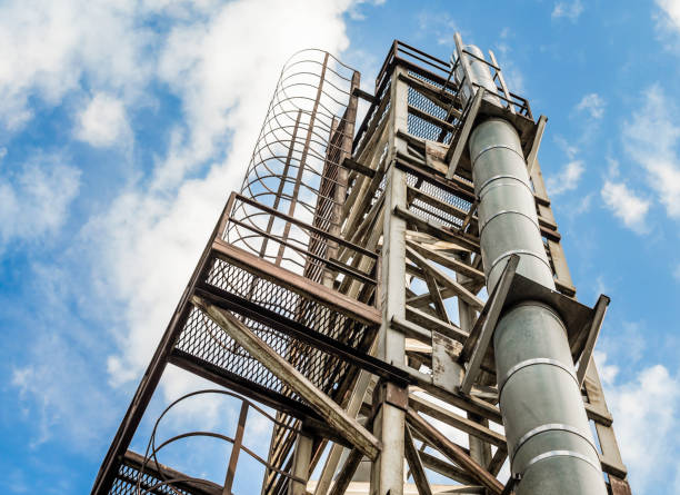 tower with a pipe and a ladder against a blue sky and clouds