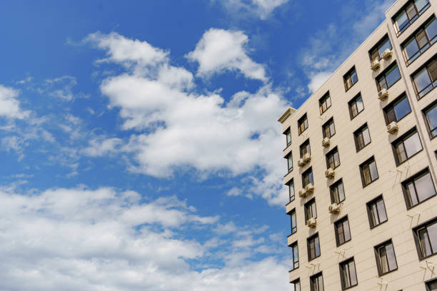 A typical multi-storey apartment modern building against the background of the sky with clouds. Cityscape.