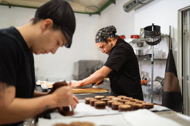 istock Two talented pastry chefs collaborating, cutting cakes and organizing cookies in a bustling kitchen setting 2188994935