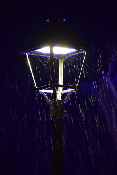 Sitting in the middle of the street at a busy intersection with the lights steaming in the rain during a storm