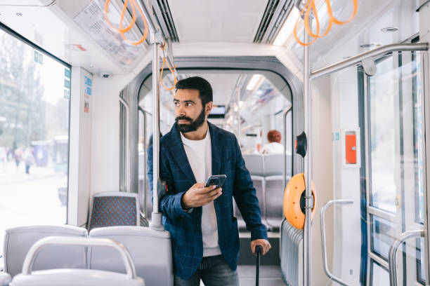 istock A businessman uses his phone while standing in a public transport 2188996006