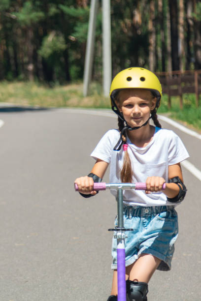istock Happy child riding scooter in summer with helmet 2188998767