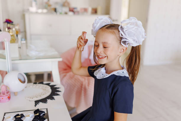 istock A little girl in a school uniform preens herself at a dressing table. 2188998934