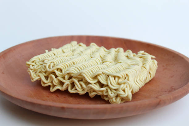 Square instant noodles before cooked, on wooden background, isolated on white background