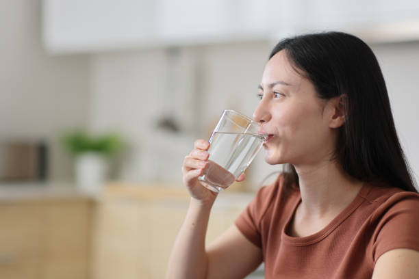 istock Asian woman drinking water in the kitchen 2189002574