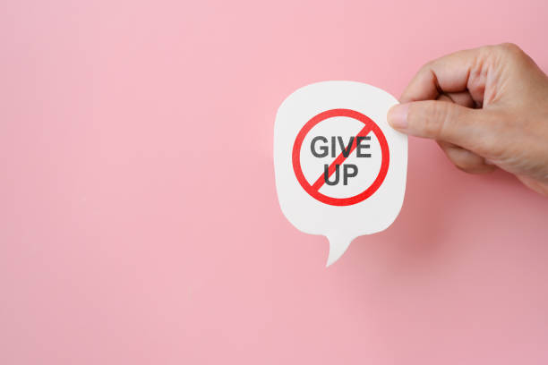 hand hold real speech bubble paper cut with don't give up on pink background