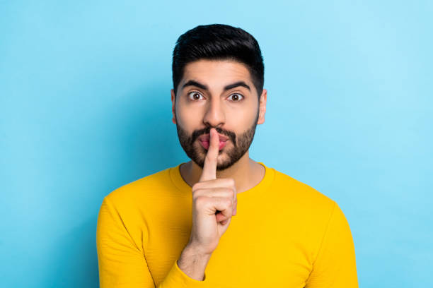 istock Photo of serious confident guy dressed yellow pullover finger lips asking keep silence isolated blue color background 2189003394
