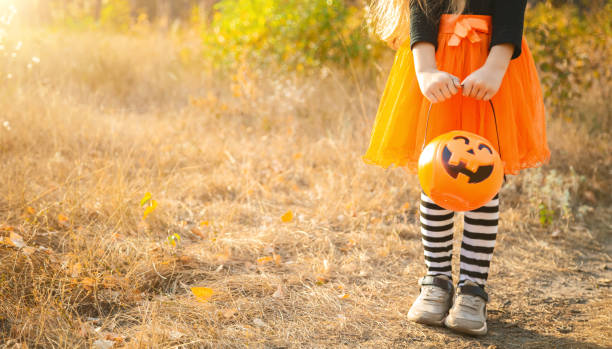 istock Closeup of unrecognizable child holding Halloween basket shaped as Jack o lantern while trick or treating, copy space 2189004464