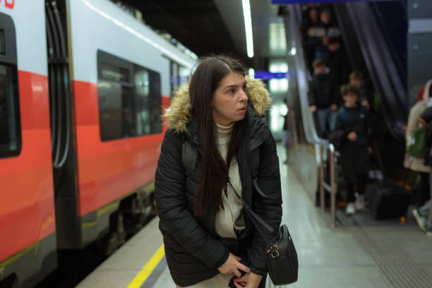 istock A woman buttons her jacket at a subway station 2189004562