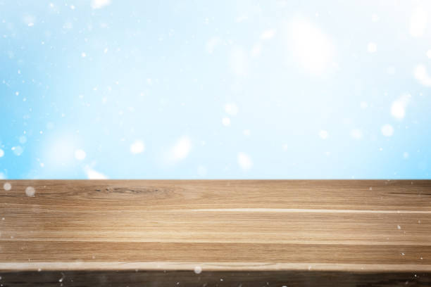 istock Empty wooden table over blue snowy background. Winter backdrop with falling snowflakes and rustic desk. 2189008313