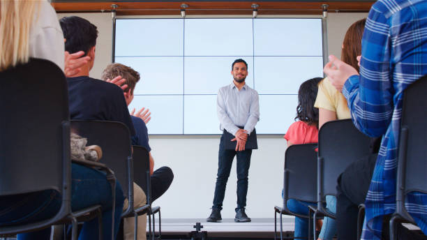 istock High School Or University Students Clapping Male Teacher Giving Presentation In Front Of Screen 2189009077