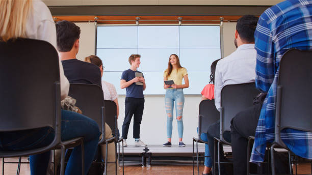 istock Two College Students Giving Presentation To High School Or University Class In Front Of Screen 2189009159