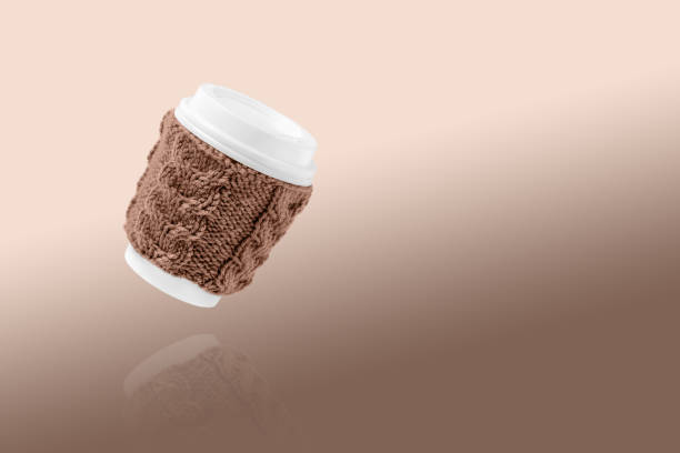 Cup for takeaway coffee Cup made of cardboard for takeaway coffee with knitted cover and white lid. Concept of takeaway coffee, walking, energetic life. Demonstrating the colors of 2025 - Mocha Mousse. food sample cups stock pictures, royalty-free photos & images