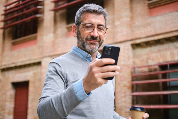 istock Middle-aged businessman using smartphone and holding coffee in barcelona 2189011521
