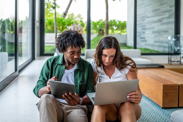 istock Young Adults Collaborating on Digital Devices in a Modern Living Space 2189011799