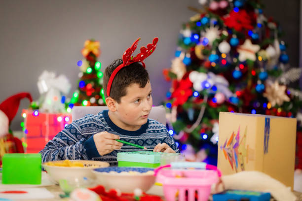 istock Happy teenage boy decorating a Christmas box 2189013417