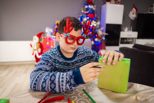istock Happy teenage boy decorating a Christmas box 2189013469